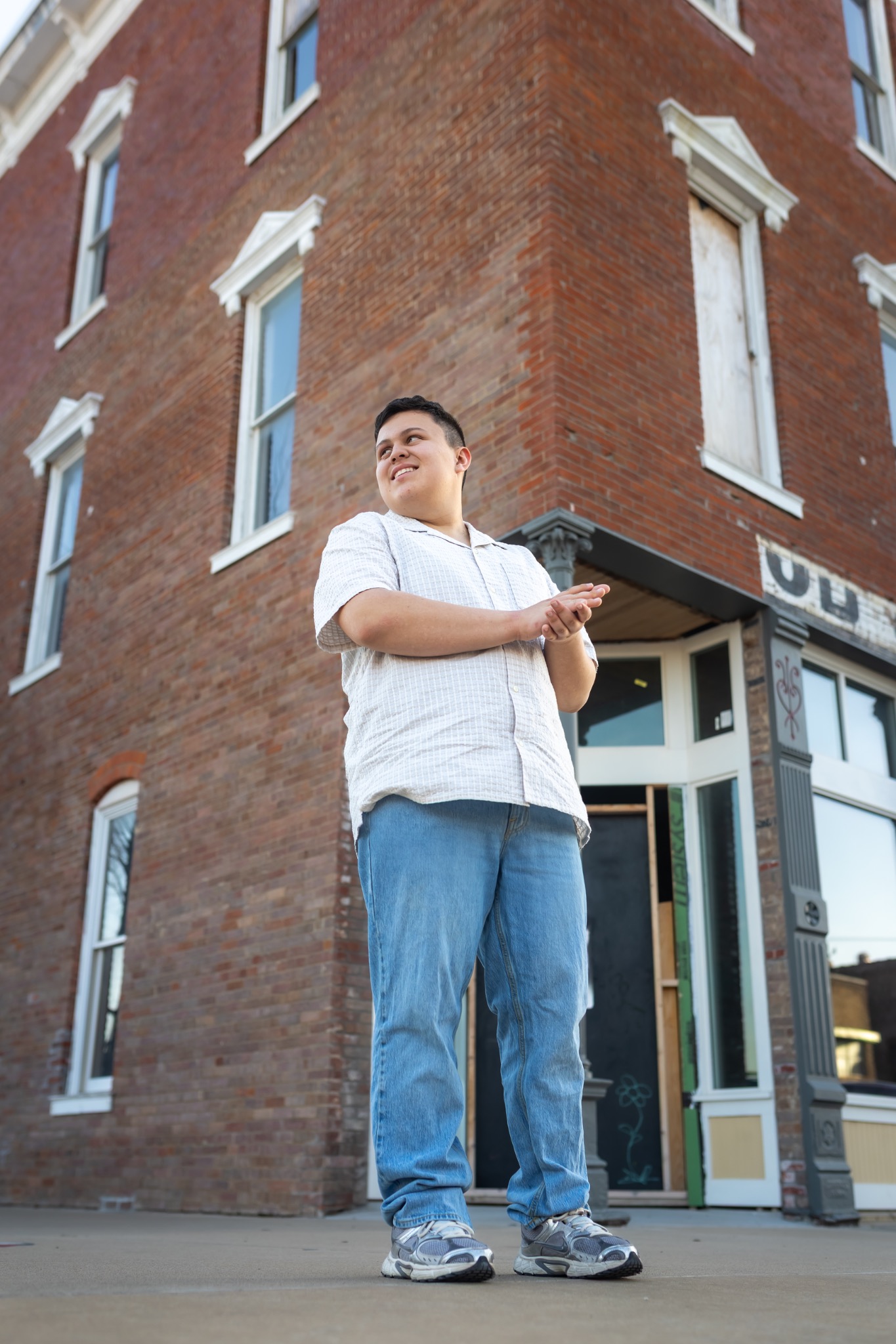 Andy Roberts standing outside a brick building in a white shirt and jeans