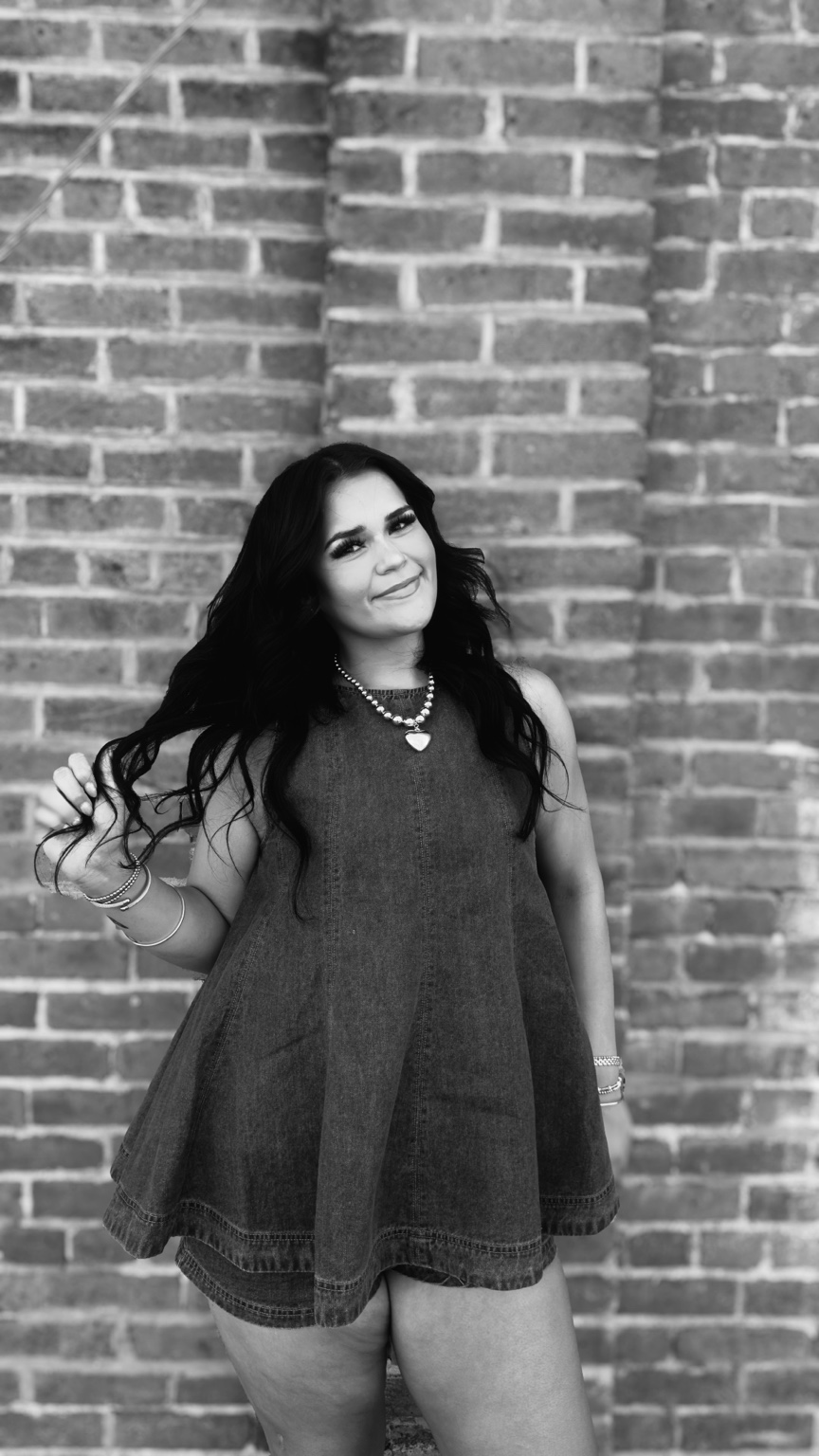Black and white portrait of a woman playing with her hair against a brick wall